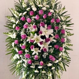 Standing floral spray with pink roses and white lilies on a black easel