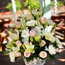 Pink roses and white lilies arranged in a clear glass bowl