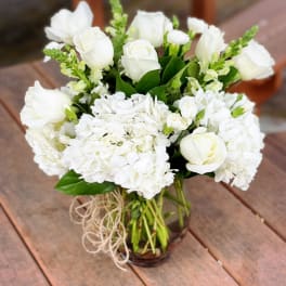 White roses and hydrangeas arranged in a glass vase