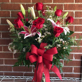 Red roses and lilies in a glass vase with a large red bow