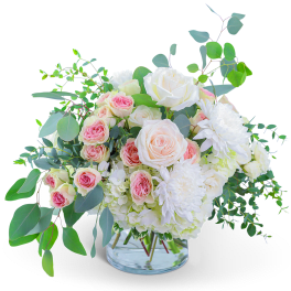 Pink and white roses with white blooms in a clear glass vase