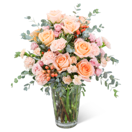 Peach and pink roses with carnations in a clear glass vase