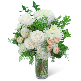 White roses and chrysanthemums in a clear glass vase with greenery