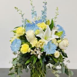 Blue and yellow floral arrangement in a glass vase with a "It's a Boy" topper