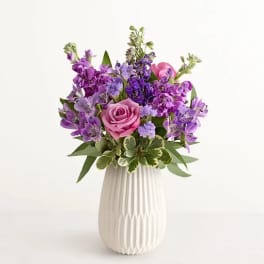 Purple and pink flower arrangement in a white vase