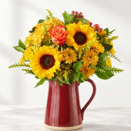 Sunflower and rose bouquet in a red ceramic pitcher