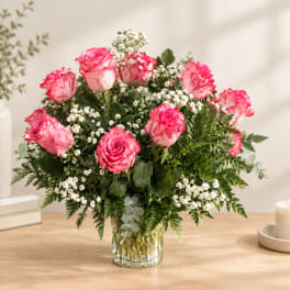 Pink roses arranged in a clear glass vase with white filler flowers