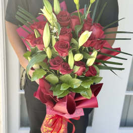 Bouquet of red roses and yellow lily buds wrapped in pink paper