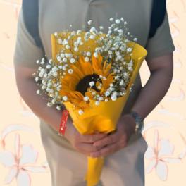 Sunflower bouquet wrapped in yellow paper with baby's breath