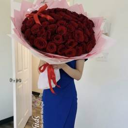 Large bouquet of red roses wrapped in pink paper with a red ribbon
