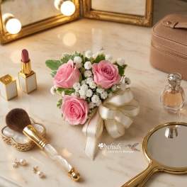 Small bouquet of pink roses and white filler flowers with a ribbon bow