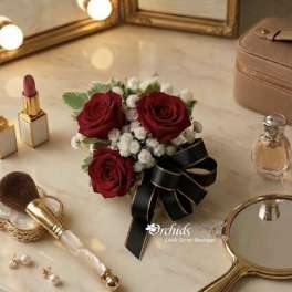 Small bouquet of red roses with white filler flowers and a black ribbon bow