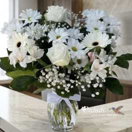 White mixed flower bouquet in a glass vase with a ribbon