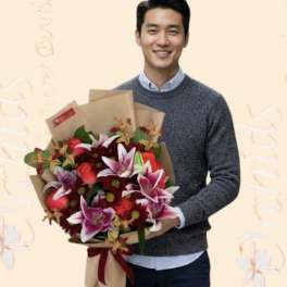 Man holding a bouquet of red and pink flowers wrapped in brown paper