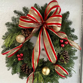 Christmas wreath with red and gold ribbon, pinecones, and ornaments