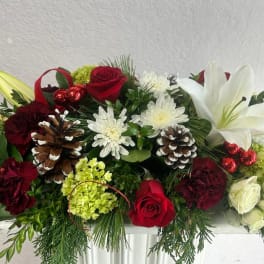 Holiday floral arrangement with red roses, white lilies, and pinecones