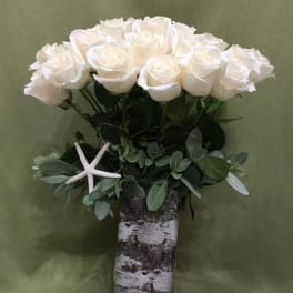 White roses in a birch vase with greenery and a starfish accent
