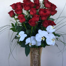 Red roses and white orchids arranged in a tall gold vase