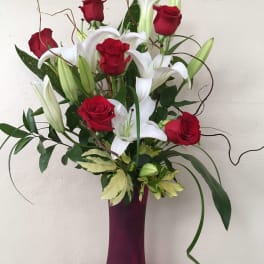 Red roses and white lilies in a tall purple vase