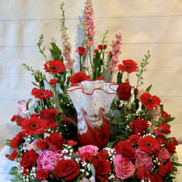 Large red and pink floral arrangement in a marbled vase