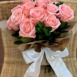 Bouquet of pink roses wrapped with brown paper and a white ribbon