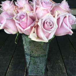 Pink roses arranged in a tall square glass vase