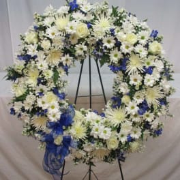 Large white and blue floral wreath on a black stand