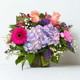 Mixed bouquet with hydrangea, roses, and gerbera daisies in a glass vase