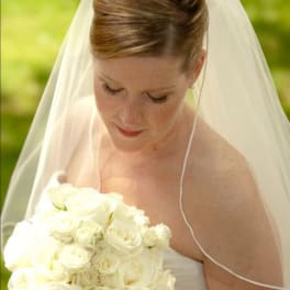 Bride holding a bouquet of white roses under a veil