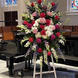 Large standing floral spray with pink roses, orchids, and lavender blooms