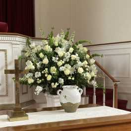 Large white floral arrangement beside a wooden cross in a church