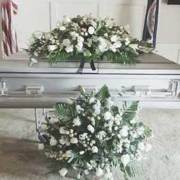 White floral sprays on a silver casket in a funeral setting