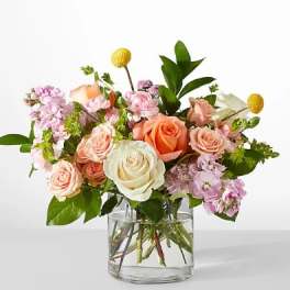 Mixed bouquet of roses and pink blooms in a clear glass vase