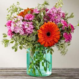Pink and orange mixed bouquet in a turquoise glass vase