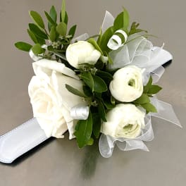 White rose and ranunculus bouquet with green foliage and white ribbon