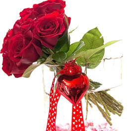 Red roses in a clear glass vase with a red heart ornament