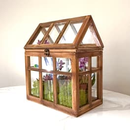 Wooden terrarium with purple orchids and succulents inside