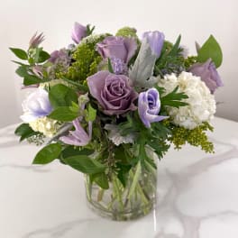 Lavender roses and white hydrangeas in a clear glass vase