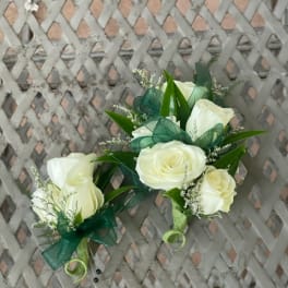 White rose corsages with green ribbon accents