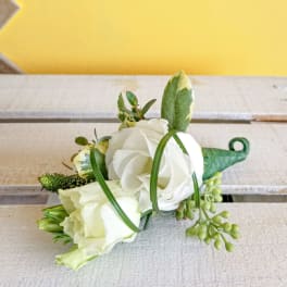 White rose boutonniere with green accents and berries