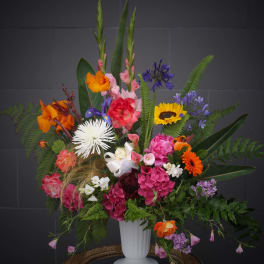 Colorful mixed flower arrangement in a white pedestal vase