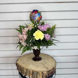 Mixed pastel bouquet in a dark vase with a birthday balloon