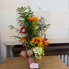 Tall autumn floral arrangement with orange blooms in a woven vase