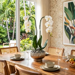 White orchid plant in a ribbed metallic bowl on a dining table