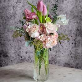 Pink tulips and pale roses arranged in a clear glass vase