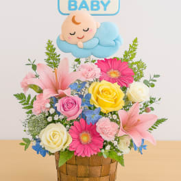 Basket arrangement with pink lilies, roses, and a baby topper
