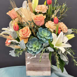 Mixed bouquet with roses, tulips, lilies, and succulents in a wooden box
