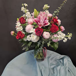 Pink and red roses with lilies in a glass vase
