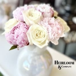 Bouquet of pale pink peonies and cream roses in a white vase