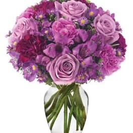 Purple rose bouquet in a clear glass vase